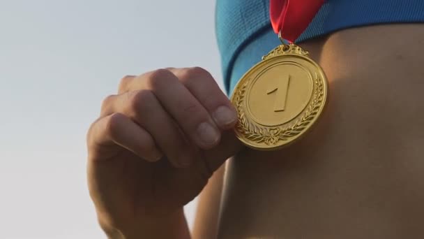 Onnellinen urheilija iloitsee voitostaan kilpailussa ja koskettaa kultamitalia
 - Materiaali, video