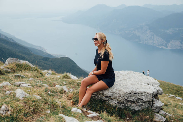 Side view of blonde woman posing on boulder on background of river valley - Fotografie, Obrázek
