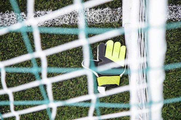 Top view of goalkeeper gloves lying on soccer pitch. - Foto, afbeelding