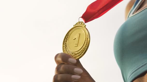 Atleta femminile Biracial mostrando medaglia d'oro davanti alla macchina fotografica, il successo e la vittoria
 - Filmati, video