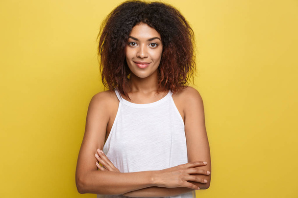 Headshot portrait of beautiful attractive African American woman posting crossed arms with happy smiling. Yellow studio background. Copy Space - Foto, afbeelding