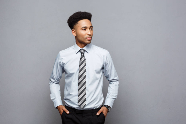 Conceito de negócio - Feliz confiante profissional afro-americano empresário posando sobre fundo cinza
. - Foto, Imagem