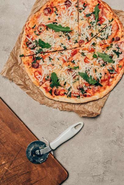  Pizza italiana y cortador de pizza sobre fondo claro
 - Foto, Imagen