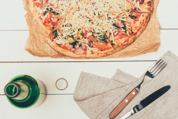 Italian pizza and opened bottle on white wooden background - Photo, Image