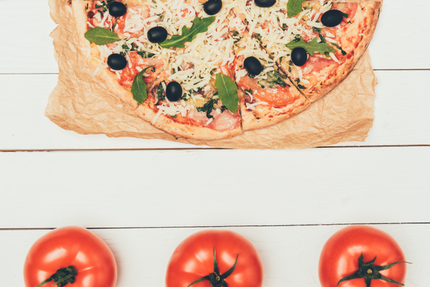 Delicious Italian pizza and red tomatoes on white wooden background - Fotografie, Obrázek