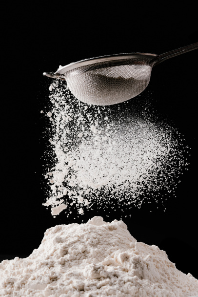 flour falling from sieve on pile isolated on black - Foto, Imagem