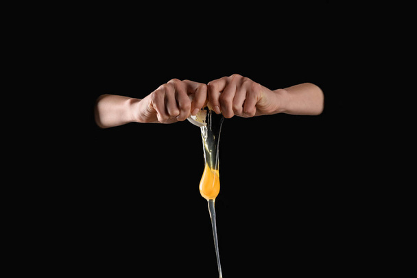 cropped image of woman dropping broken chicken egg isolated on black - Fotoğraf, Görsel