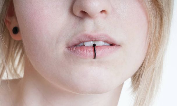 проколоті жіночі губи з вертикальним ламповим пірсингом або кільцем для губ
 - Фото, зображення
