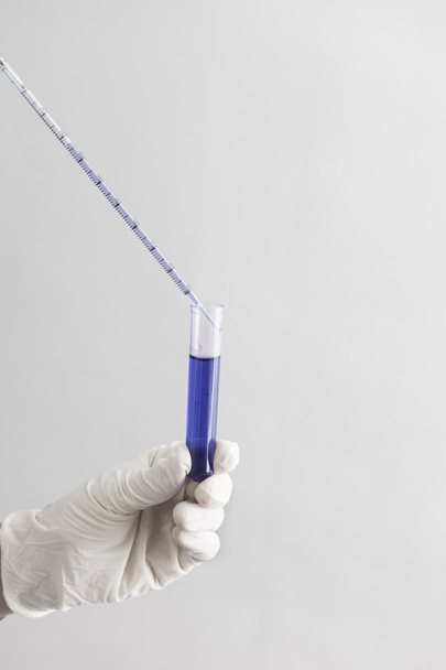 Main tenant un tube à essai avec un liquide bleu
 - Photo, image