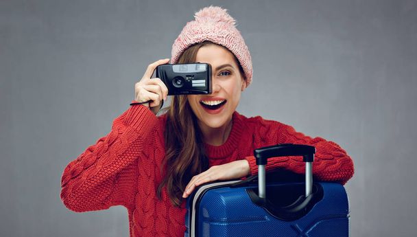 smiling woman in winter clothes with case holding camera, winter vacation travel concept  - 写真・画像