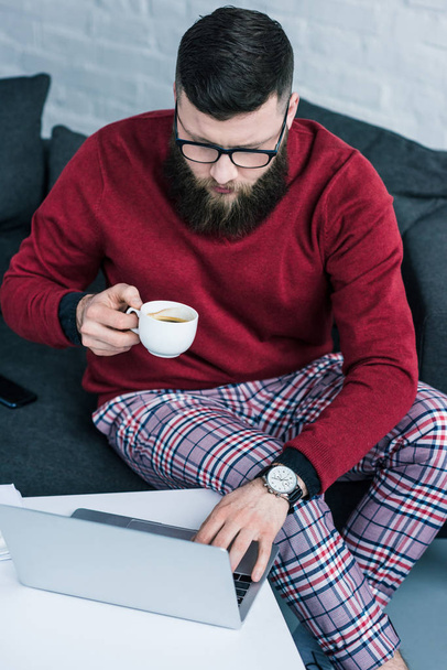 visão de alto ângulo de homem de negócios com xícara de café usando laptop
 - Foto, Imagem