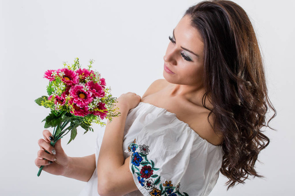 Ελκυστική νεαρή γυναίκα μελαχρινή που κρατά φρέσκα λουλούδια  - Φωτογραφία, εικόνα