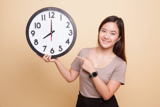 Young Asian woman point to a clock. - Foto, Bild