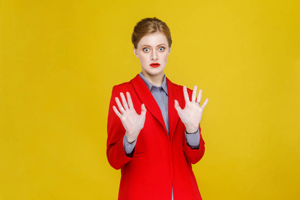 redhead businesswoman in red jacket looking at camera with shocked face and big eyes, fear concept  - 写真・画像