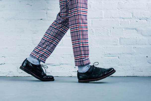 cropped shot of man in stylish shoes walking against white brick wall - Foto, Bild