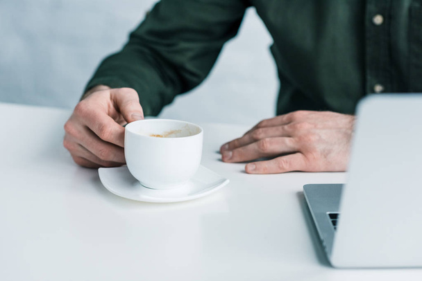 обрезанный снимок бизнесмена с чашкой кофе на рабочем месте
 - Фото, изображение
