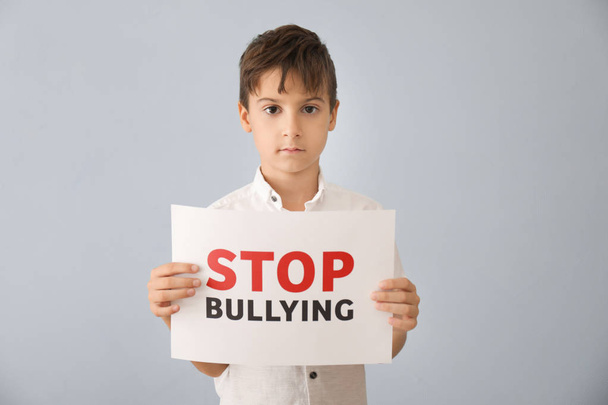 Little boy holding sign with words "Stop Bullying" on grey background - Фото, зображення