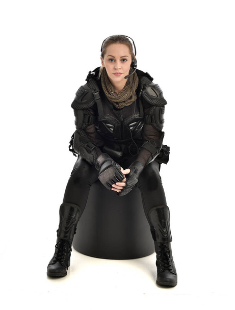 volledige lengte portret van het dragen van vrouwelijke zwarte tactische pantser, crouching pose, geïsoleerd op witte studio achtergrond. - Foto, afbeelding