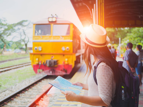 Primer plano una hermosa mujer con la mochila sosteniendo mapa y esperando el tren
.  - Foto, Imagen