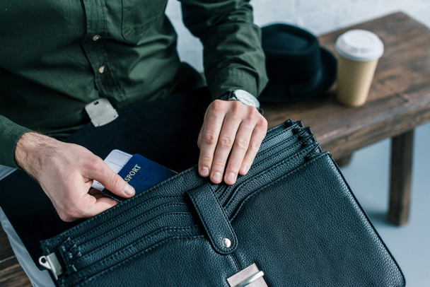 cropped shot of businessman putting passport and ticket into suitcase - Valokuva, kuva