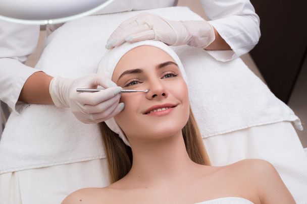 Keep your beauty! Beautiful woman getting skin cleaning and face treatment at beauty salon cosmetologist takes care of her face. - Photo, Image