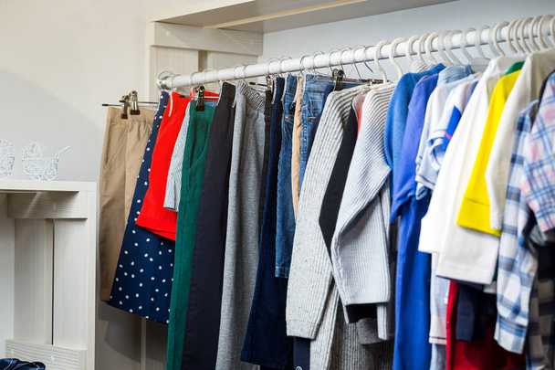 Одежда висит на полке в дизайнерском магазине
 - Фото, изображение