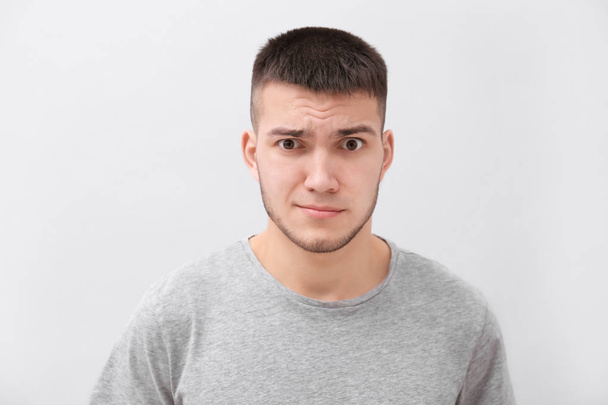 Emotional young man with dyed eyebrows on light background - 写真・画像