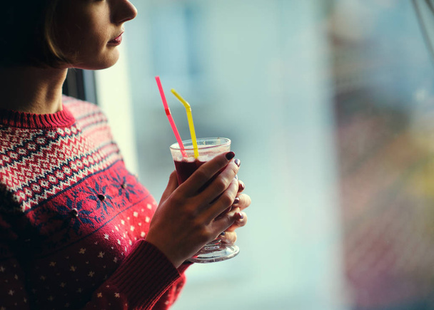 Woman holding a glass of mulled wine while looking out of the wi - Photo, image