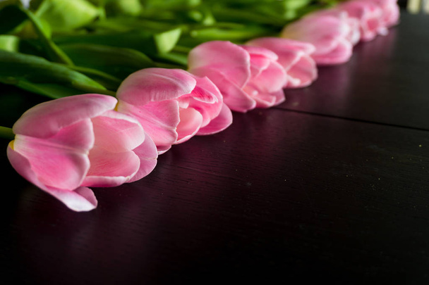 Border from bright pink tulips flowers on black wooden backgroun - Photo, Image