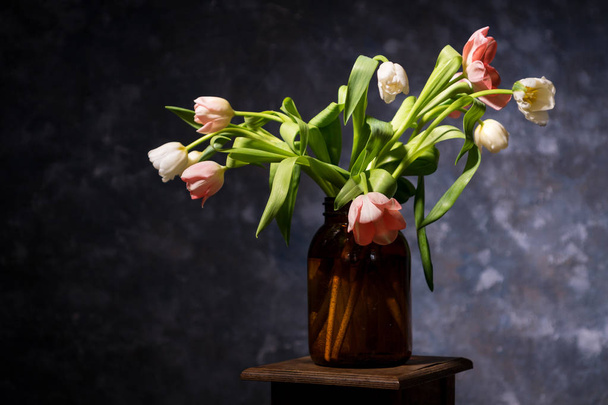 witte en roze tulpen in de vaas op de achtergrond grijs-blauw - Foto, afbeelding