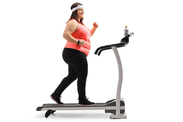 Full length profile shot of an overweight woman exercising on a treadmill isolated on white background - Foto, Imagem