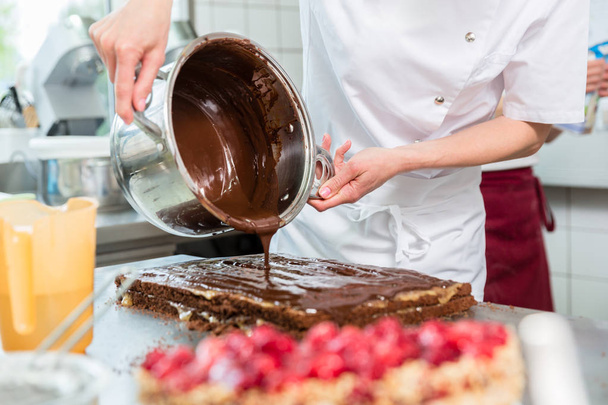 Confeiteiro colocando chocolate no bolo
 - Foto, Imagem