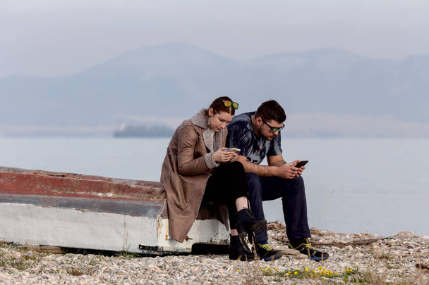 Nuori pari rannalla puhelimilla
 - Valokuva, kuva