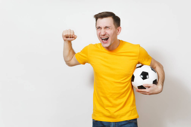 インスピレーション若いヨーロッパ人やファンは黄色いユニフォームで選手サッカー ボールを保持する、お気に入りのサッカー チームを応援、表情豊かな白い背景で隔離の手の身振りを入れて話します。ライフ スタイルのコンセプト。コピー スペース. - 写真・画像
