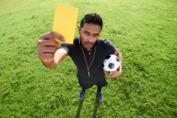Μεγάλη γωνία θέα της μικτής φυλής διαιτητής ποδοσφαίρου δείχνει κίτρινη κάρτα στη φωτογραφική μηχανή - Φωτογραφία, εικόνα