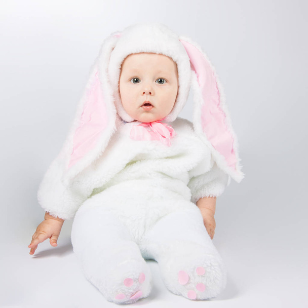 little cute baby in a white Bunny suit. The child sits on the floor. - 写真・画像
