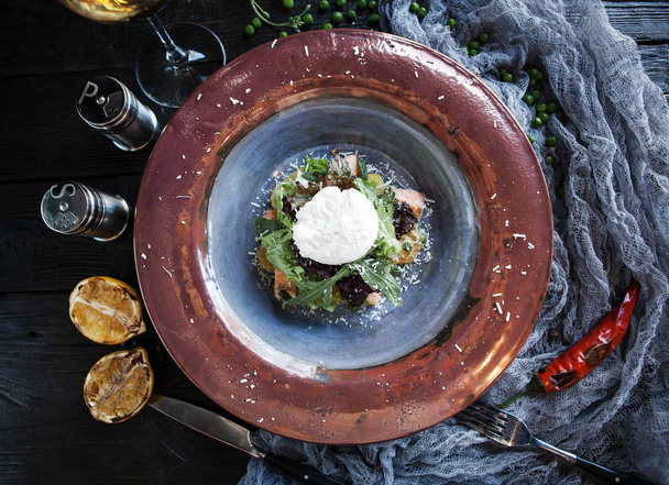 Hermosa porción de ensalada con huevo escalfado y una copa de vino en una mesa de madera oscura
 - Foto, Imagen