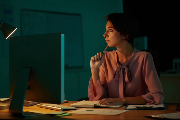 Pensive business lady working in dark office - Zdjęcie, obraz