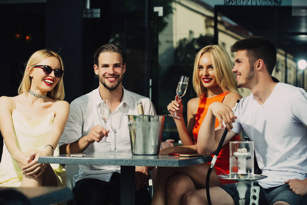 Happy friends vapor hookah and drink alcohol in bar lounge - Foto, Imagen