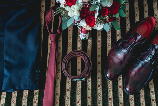 ζώνη, γραβάτα, το κοστούμι, παπούτσια και γαμήλια ανθοδέσμη σε ένα vintage καναπέ - Φωτογραφία, εικόνα