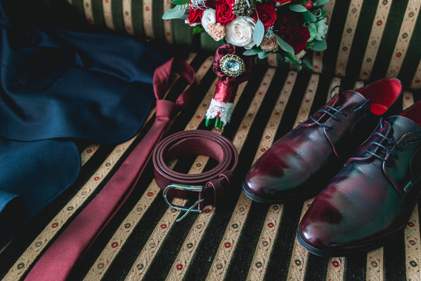 Gürtel, Krawatte, Anzug, Schuhe und Brautstrauß auf einem Vintage-Sofa - Foto, Bild