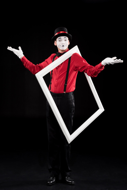 mime showing shrug gesture and holding frame on shoulder isolated on black - Foto, immagini
