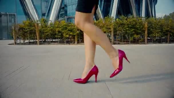 Weibliche Beine in Stöckelschuhen, die durch die urbane Straße laufen. Füße einer jungen Geschäftsfrau in hochhackigen Schuhen, die in der Stadt unterwegs ist. Mädchen auf dem Weg zur Arbeit. Zeitlupe Nahaufnahme - Filmmaterial, Video