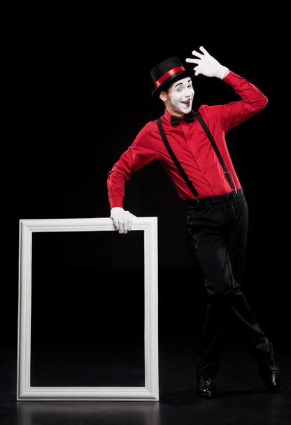 happy mime leaning on frame and waving hand isolated on black - Zdjęcie, obraz