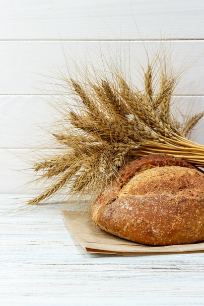 Хліб і пшениця на білому дерев'яному фоні
 - Фото, зображення