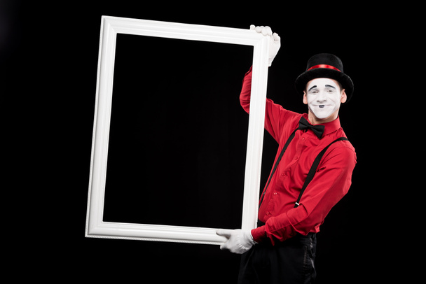 smiling mime holding frame isolated on black - Foto, Imagen