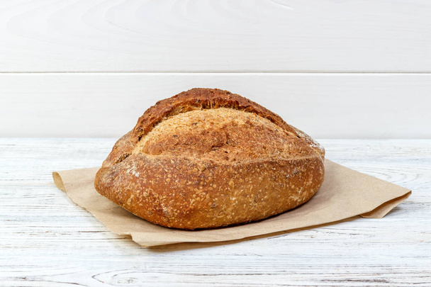 Fresh bread on wooden table. Bread on paper bag - Фото, зображення