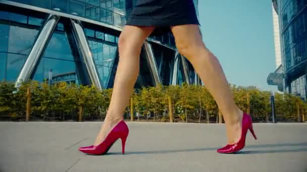 Sexy mujer piernas en zapatos de tacón alto rojo caminando en la calle urbana de la ciudad. Steadicam estabilizado tiro Lente llamarada. Patas femeninas en zapatos de tacón alto en la calle de la mañana
. - Imágenes, Vídeo
