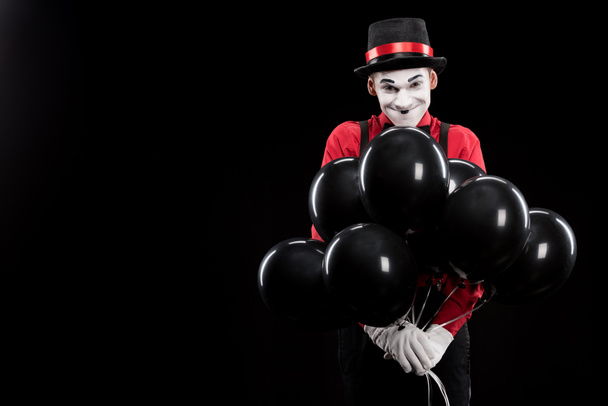 Grijnzende mime met bundel van helium ballonnen geïsoleerd op zwart - Foto, afbeelding