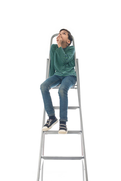 le garçon s'assoit sur une échelle et lève les yeux
 - Photo, image